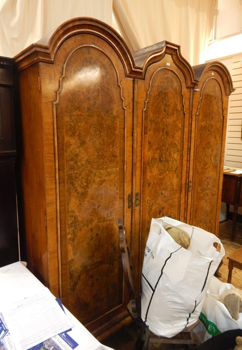 20th century figured walnut triple wardrobe in the Queen Anne revival taste, having three rounded