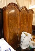 20th century figured walnut triple wardrobe in the Queen Anne revival taste, having three rounded