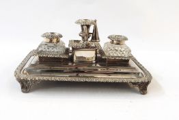 Silver plated inkstand with cut glass inkwells, on four pad feet, with a central candle holder and