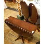 Two reproduction mahogany tilt-top tripod occasional tables with oval tops and a reproduction