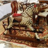 Painted wooden rocking horse with leather saddle and reins, painted in black and white dappling,