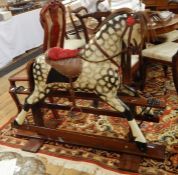 Painted wooden rocking horse with leather saddle and reins, painted in black and white dappling,