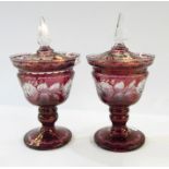 Pair of Victorian cranberry glass pedestal lidded urns with clear glass finials, rose etched