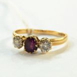 18ct gold, ruby and diamond ring, the central oval ruby flanked by smaller brilliant cut diamonds,