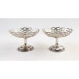 Pair of early 20th century pierced bonbon dishes, raised on stems, on stepped circular feet,