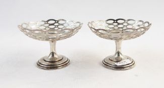 Pair of early 20th century pierced bonbon dishes, raised on stems, on stepped circular feet,