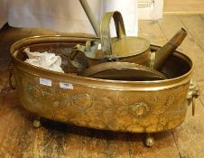 Large brass jardiniere with repousse roses, lion masks either end and rings, on four claw feet, 50cm