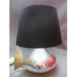 A Contemporary chrome table lamp, of squat form with dimpled decoration, having black shade, H.