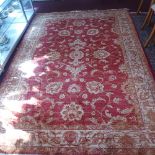 A Ziegler style carpet with floral design on a red ground contained by borders.