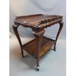A 20th Century Middle Eastern hardwood two tier drinks trolley raised on cabriole legs and castors,