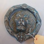 A cast iron door knocker in the form of a lion's head.