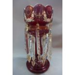 A Victorian ruby glass lustre with floral design and cut glass droplets.