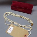 A four strand seed pearl necklace with yellow metal clasp.