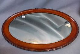 An oval mahogany wall mirror, having bevelled plate,