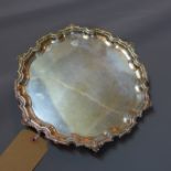 A silver salver raised on three feet with pie crust edge, hallmarked Birmingham 1962