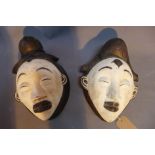 Two Punu tribal masks, Gabon, having ebonised lobed and ribbed coiffure with a white pigment face,