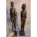 Two Kenyan carved ebonised wooden figures of man and a women in traditional dress, raised on stepped