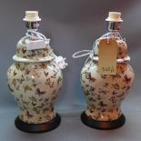 A pair of contemporary table lamps decorated with butterflies, raised on ebonised oval bases, H.