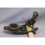 A plaster figural study of an African lady on a canoe, ebonised and polychrome decorated, with