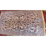 A Persian Nain part silk rug with central floral design on a cream ground contained by borders.