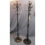 A pair of early 20th century wrought iron standard lamps with frosted glass shades in the form of