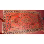 A fine North West Persian rug with floral decoration on a rouge ground contained by borders 143x79cm