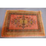 A North West Persian pink ground rug, having central floral medallion within borders, fringed, 99