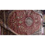 A Kashan style carpet with central floral medallion on a red ground contained by repeating floral