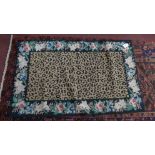 A handmade needle point rug with leopard print design on a black ground. 152x91cm