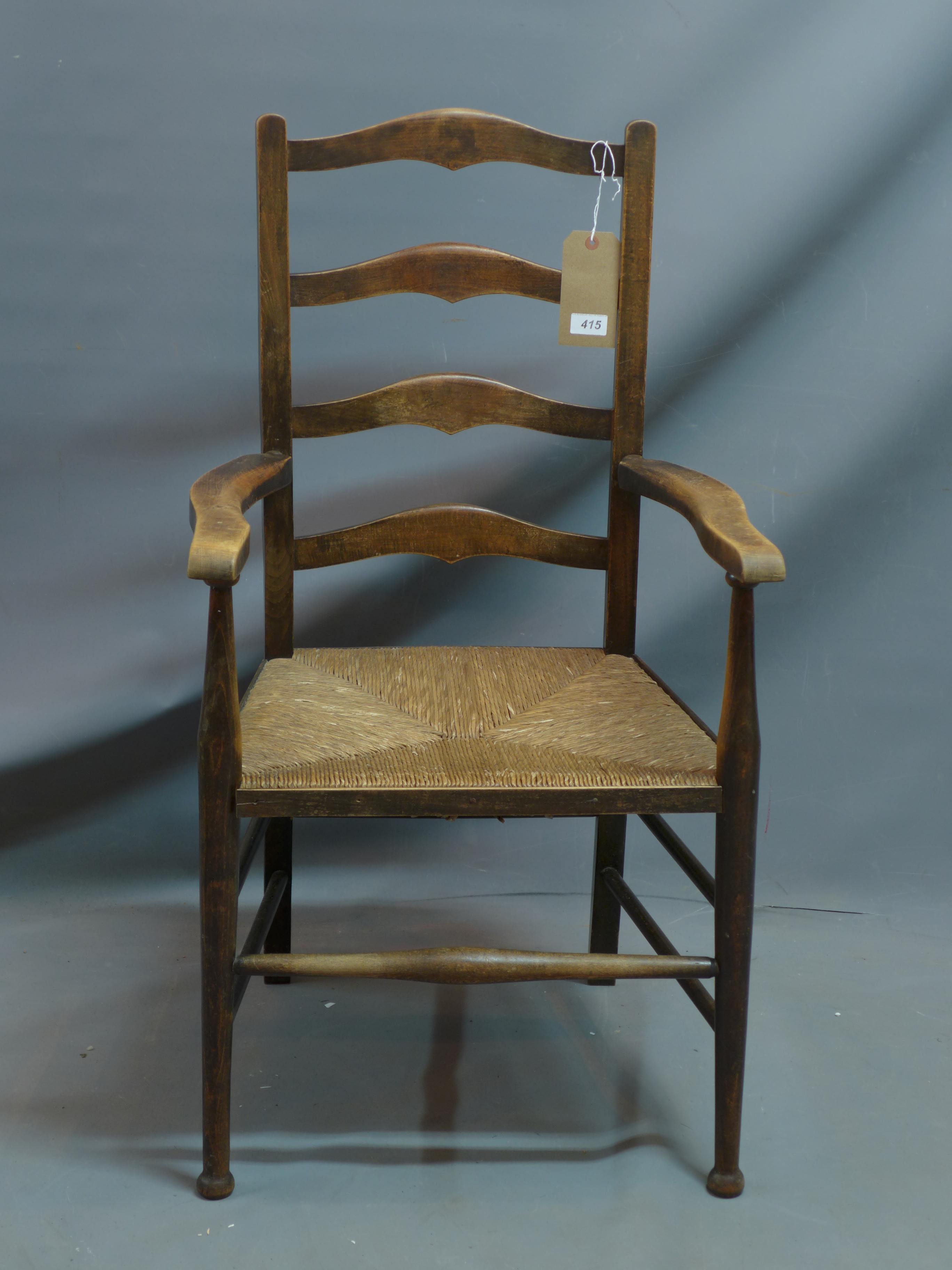 An early 20th century oak ladder back armchair with rush seat.