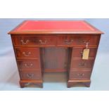 A Georgian style mahogany kneehole desk with eight drawers and one cupboard door raised on bracket