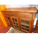 An Early 20th century French oak sideboard with three carved drawers over three glazed doors