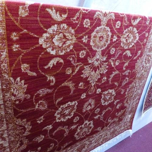 A Zeigler style carpet with floral design on a red ground contained by beige ground border.