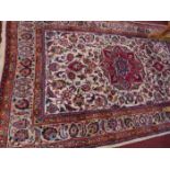 A Persian Mashad carpet with central floral medallion surrounded by floral motifs on a beige