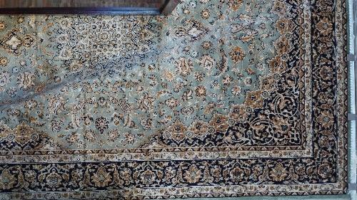 A Kashan style carpet with central floral medallion on a green ground contained by many floral