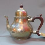 A silver three piece tea set, comprising a teapot with wooden handle and finial, a milk jug and a