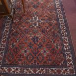 A Persian Mey Mey rug with central floral motifs on a red ground contained by floral borders on a