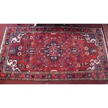 A Hamadan carpet with central floral medallion on a rouge ground contained by floral borders. 276