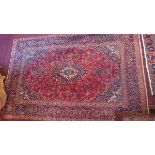 A Kashan carpet with central floral medallion on a red and blue ground contained by floral