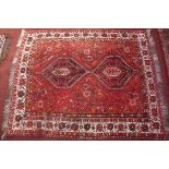 A Quashqai rug with twin geometric medallions on a red ground contained by geometric borders.