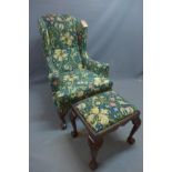 A Georgian style wing back armchair with William Morris golden lily fabric raised on ball and claw