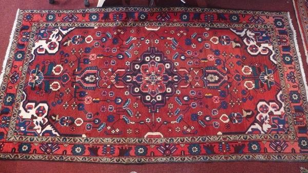 A Hamadan carpet with central floral medallion on a rouge ground contained by floral borders, 276