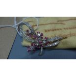 An 18ct white gold, diamond and ruby set brooch, in the form of a bow having flowers with ruby set