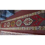 An antique Turkish runner, with five geometric pole medallion on a red ground, contained by
