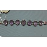A white metal and amethyst bracelet, the seven oval cut stones set in white metal mounts