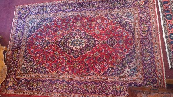 A Kashan carpet with central floral medallion on a red and blue ground contained by floral