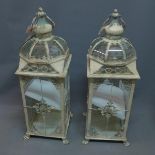 A pair of white painted storm lanterns, on paw feet, H. 73cm