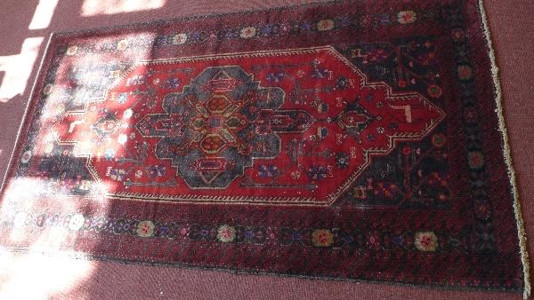 A fine North East Persian Meshad Belovch rug, having central double pendent medallion on a rouge