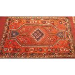 A Quashqai Shiraz carpet with central lozenge geometric medallion on an orange ground contained by