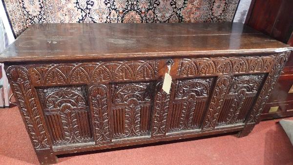 A 17th century oak panelled coffer of large proportion, with four carved panels below hinge lid